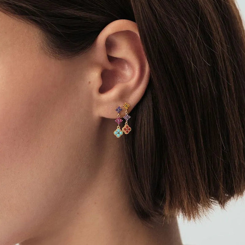 Close-up of a person wearing colorful earrings with a neutral background Joie d’Or