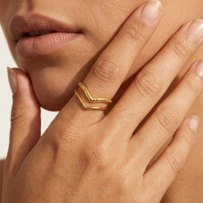 Close-up of a hand wearing a gold ring with a neutral background